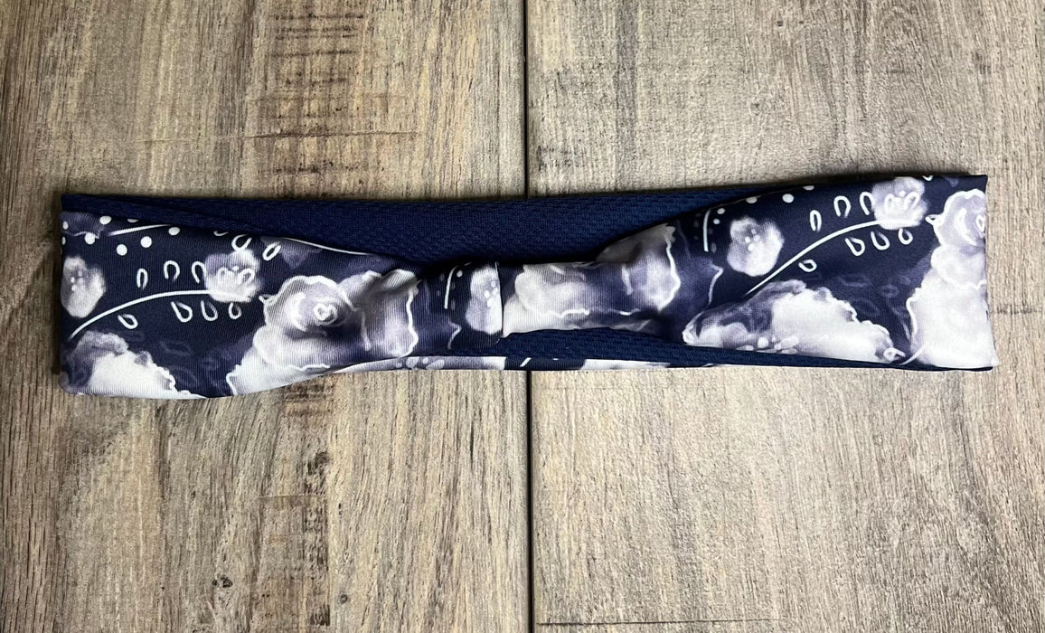 Navy blue workout headband with white floral pattern from Athena Fitness Collections on wooden surface