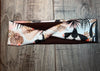 Handmade workout running headband with pink and black cactus print on brown fabric, laid on wooden surface