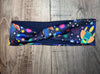 Athena Fitness colorful workout headband with star, planet, and rocket patterns on wooden surface