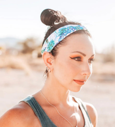 Woman wearing a Light Blue flower Headband with white flowers and green flora with light blue dri fit material 
