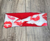 Red and white workout headband with red lip print pattern, handmade and twisted style on wood surface