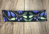 Handmade workout headband with blue and green floral pattern on black, on wood background