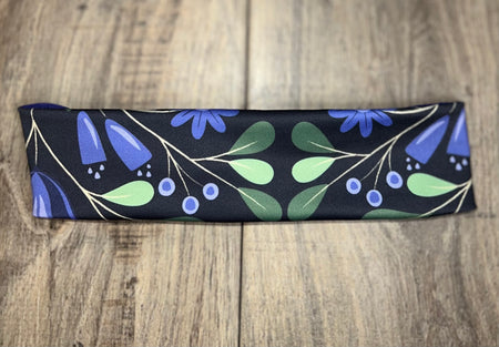 Handmade workout headband with blue and green floral pattern on black, on wood background