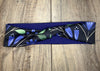 Handmade workout headband with blue floral pattern and green leaves on navy background, laid on wooden surface