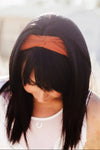 Woman outdoors wearing orange workout headband, white lace top, and red pants in sunlit field