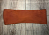 Handmade rust-colored ribbed workout headband on light wooden floor, Athena Fitness Collections