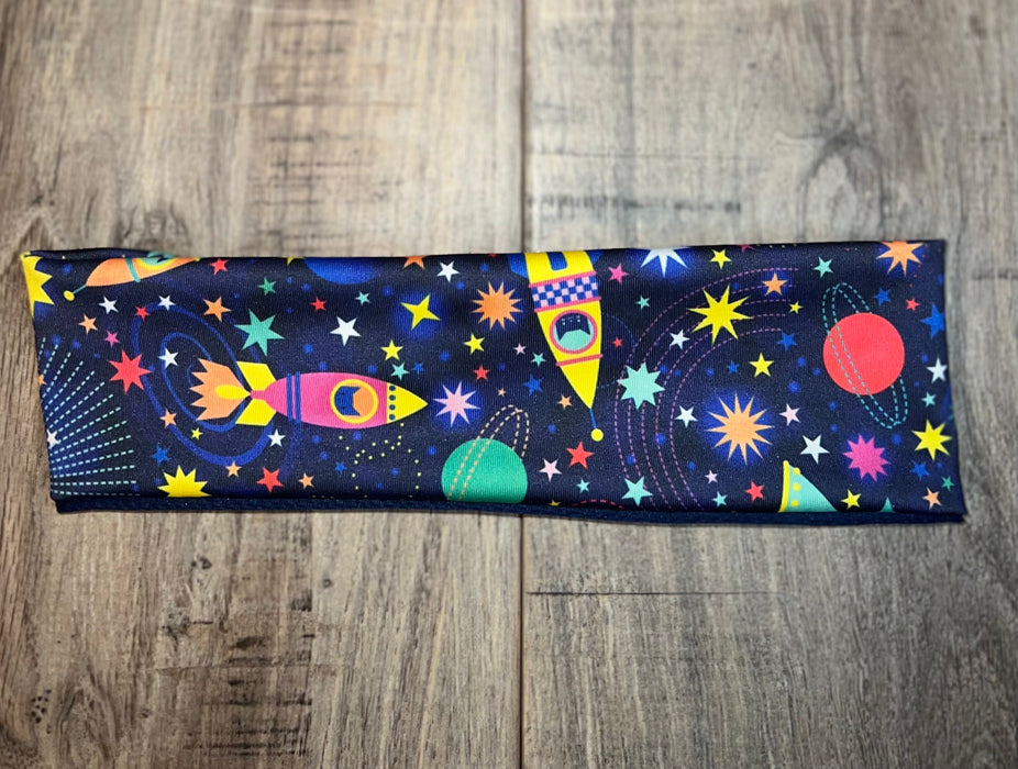 Colorful space-themed workout headband with rockets, stars, and planets on wooden floor