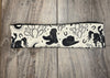 Handmade workout headband with black western cowboy design including boots, hat, horse, cactus, and horseshoes on cream fabric