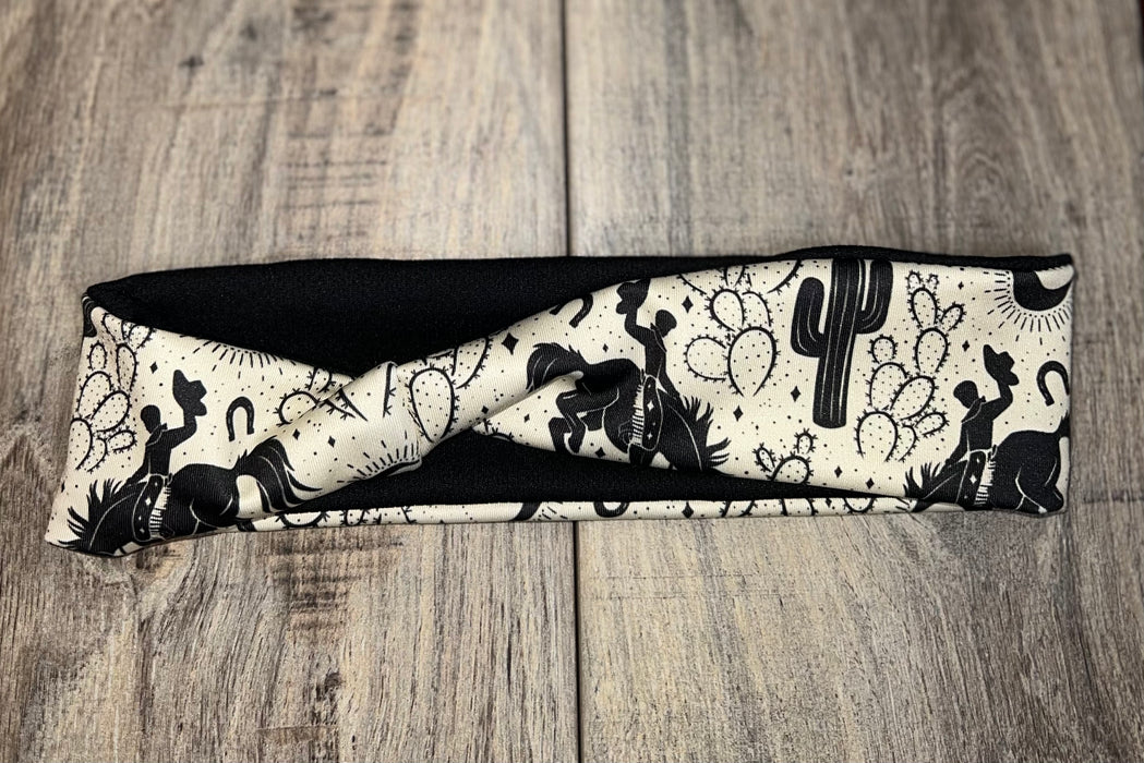 Handmade workout headband with black and white cowboy, cactus, horseshoe, and sun pattern on wood background