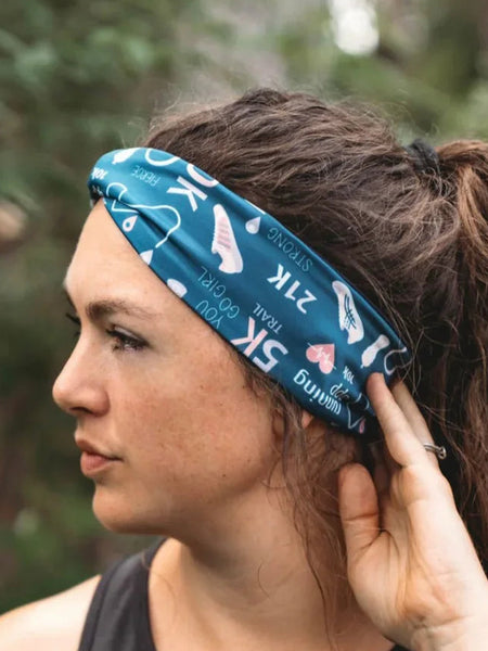 Woman wearing a blue workout headband with running and fitness icons, styled with a black tank top outdoors