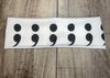 White workout headband with repeated black semicolon design on wooden surface, Athena Fitness Collections