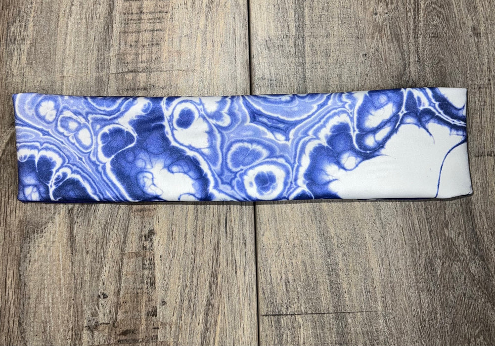 Blue and white marble-patterned handmade workout headband on wooden surface