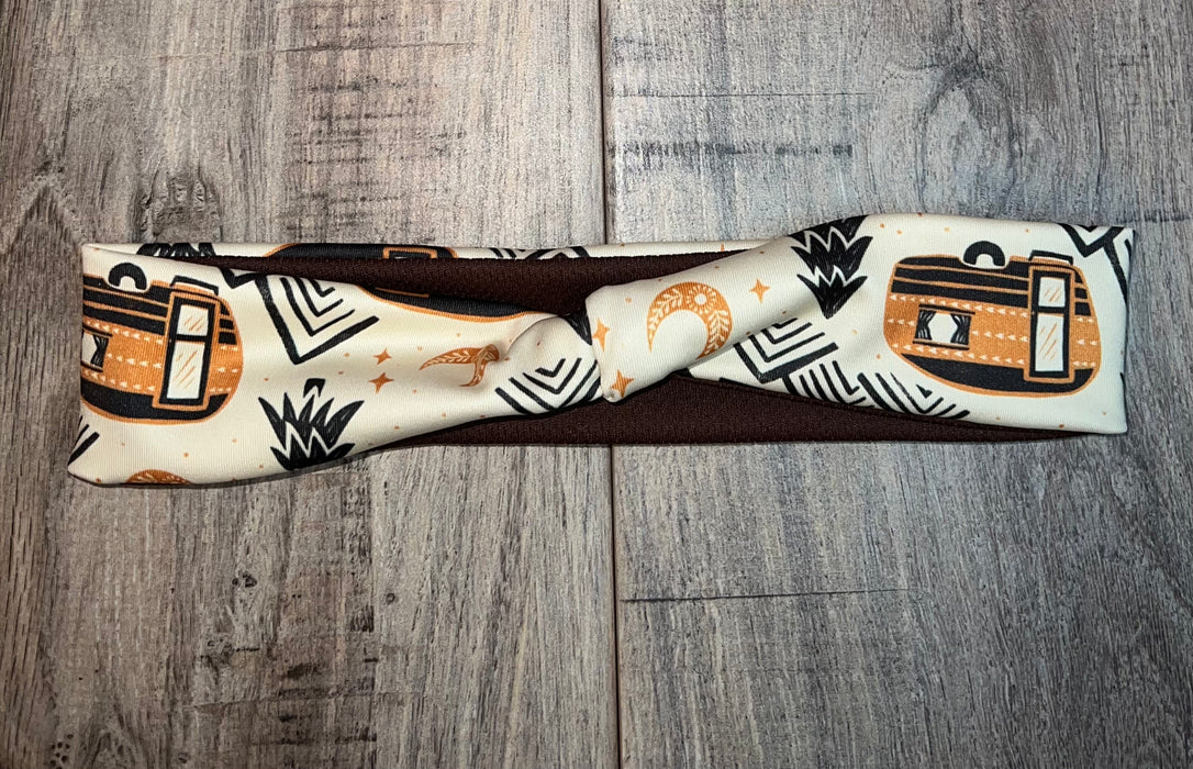 Handmade fabric vanlife workout headband with desert camper and moon pattern on wood background