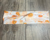 White twisted workout headband with orange Halloween pumpkin and star print on wooden surface