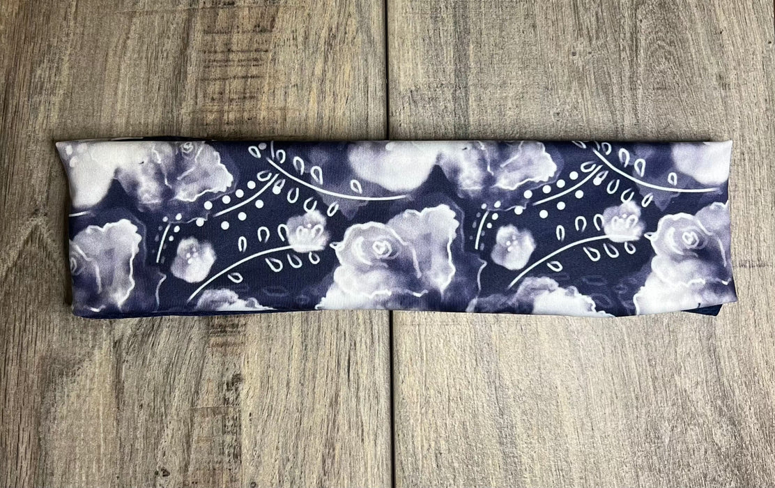 Athena Fitness handmade workout headband with navy blue and white floral pattern on wooden surface