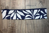 Navy blue and white workout nonslip headband with a bold leaf pattern on wooden surface