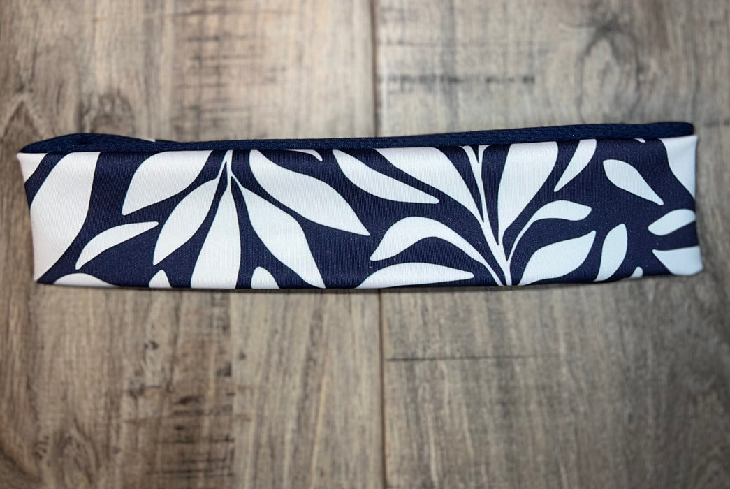 Navy blue and white workout nonslip headband with a bold leaf pattern on wooden surface