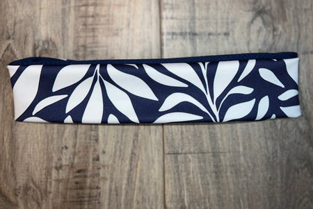Navy blue and white workout nonslip headband with a bold leaf pattern on wooden surface