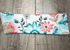 Handmade workout headband with colorful floral print in blue, pink, and green on wooden background