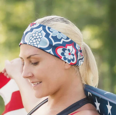 Woman wearing patterned workout headband and black tank top holding an American flag outdoors